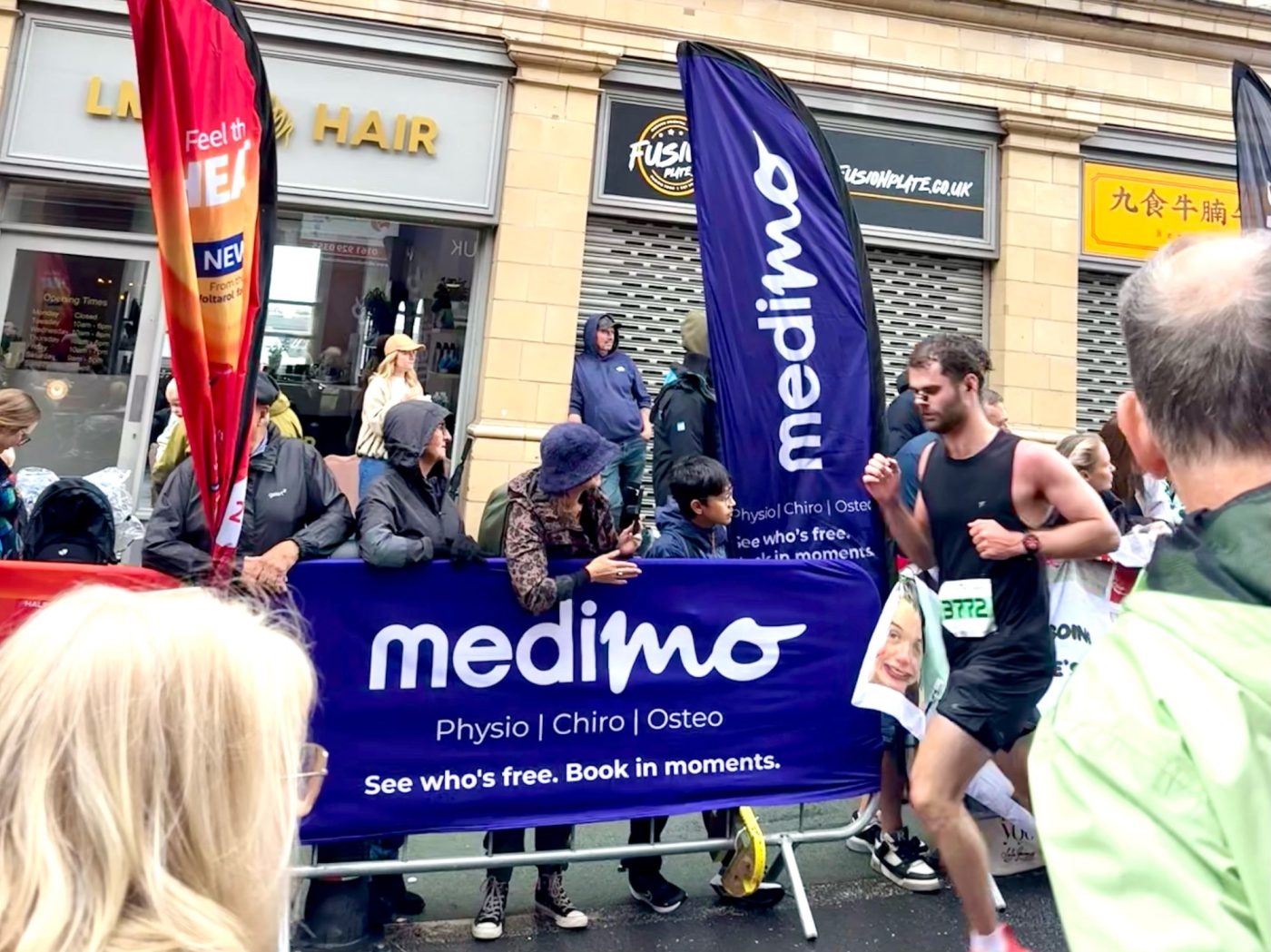 Runners passing MediMo banners and flags at the Altrincham 10K