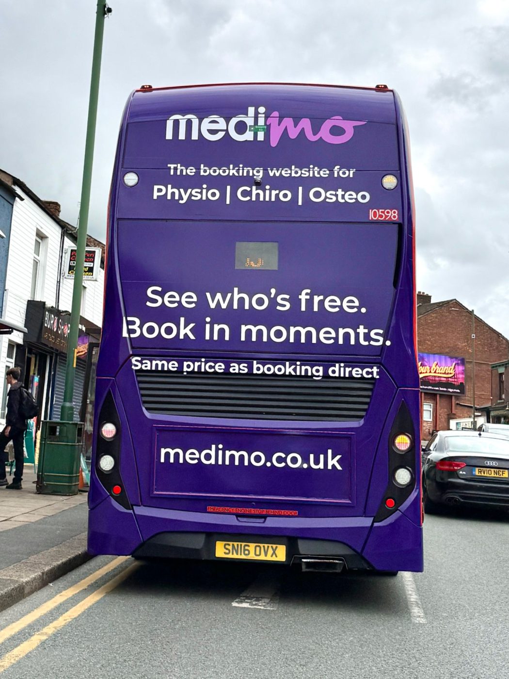 The back of a double-decker bus in MediMo purple: the booking website for physio, chiro and osteo — see who's free, book in moments